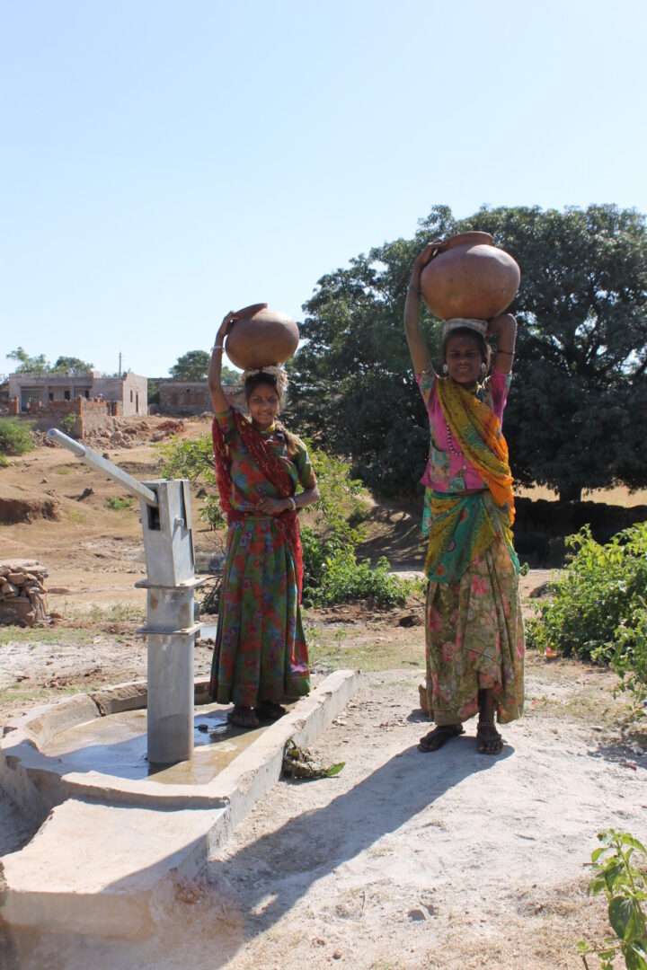 Two women carrying water from a well.